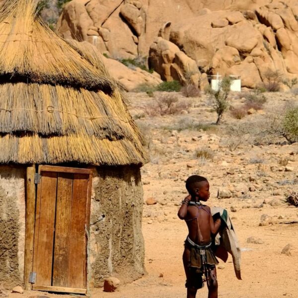 Native standing by a hut